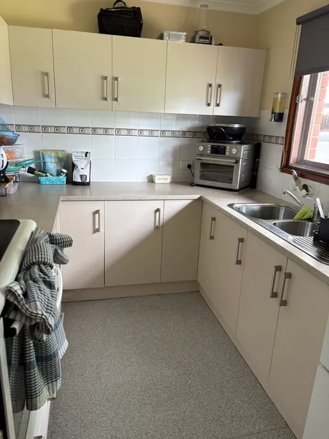 Cleaned kitchen with clear benchtops, wiped cupboard doors and a mopped floor
